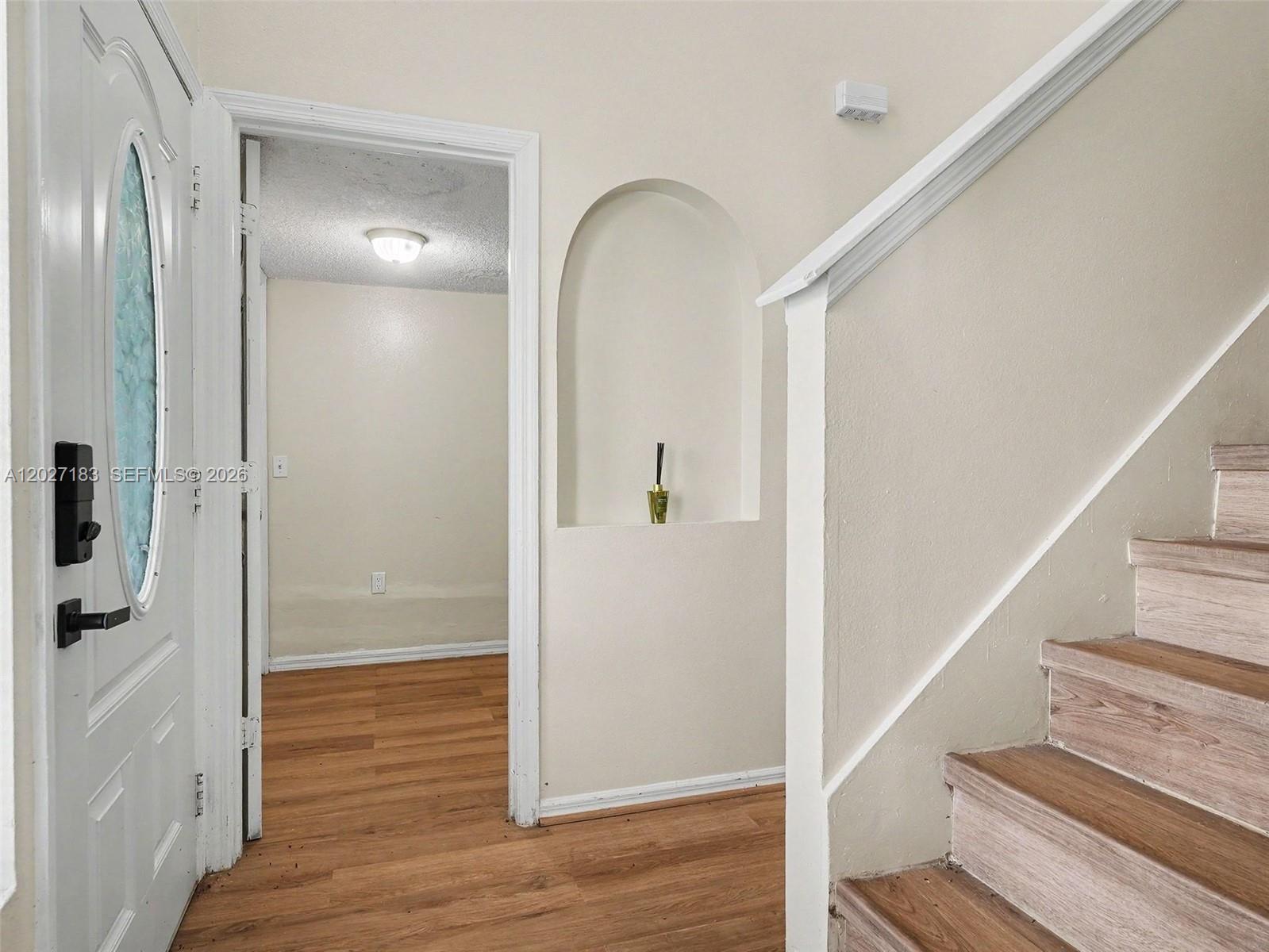 An entryway features wood-look flooring, a white front door, a recessed wall niche, and stairs — 945 Gateshead, Kissimmee FL 34758, KISSIMMEE, FL