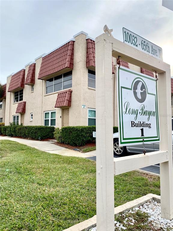 A multi-story apartment building with a sign in the foreground identifying it as Building 1 — 10032 65TH AVENUE N UNIT 17, ST PETERSBURG, FL