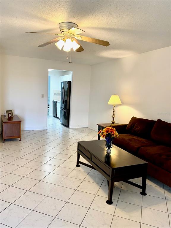 A living room features white tile floors, a ceiling fan, and a dark brown sofa — 10032 65TH AVENUE N UNIT 17, ST PETERSBURG, FL