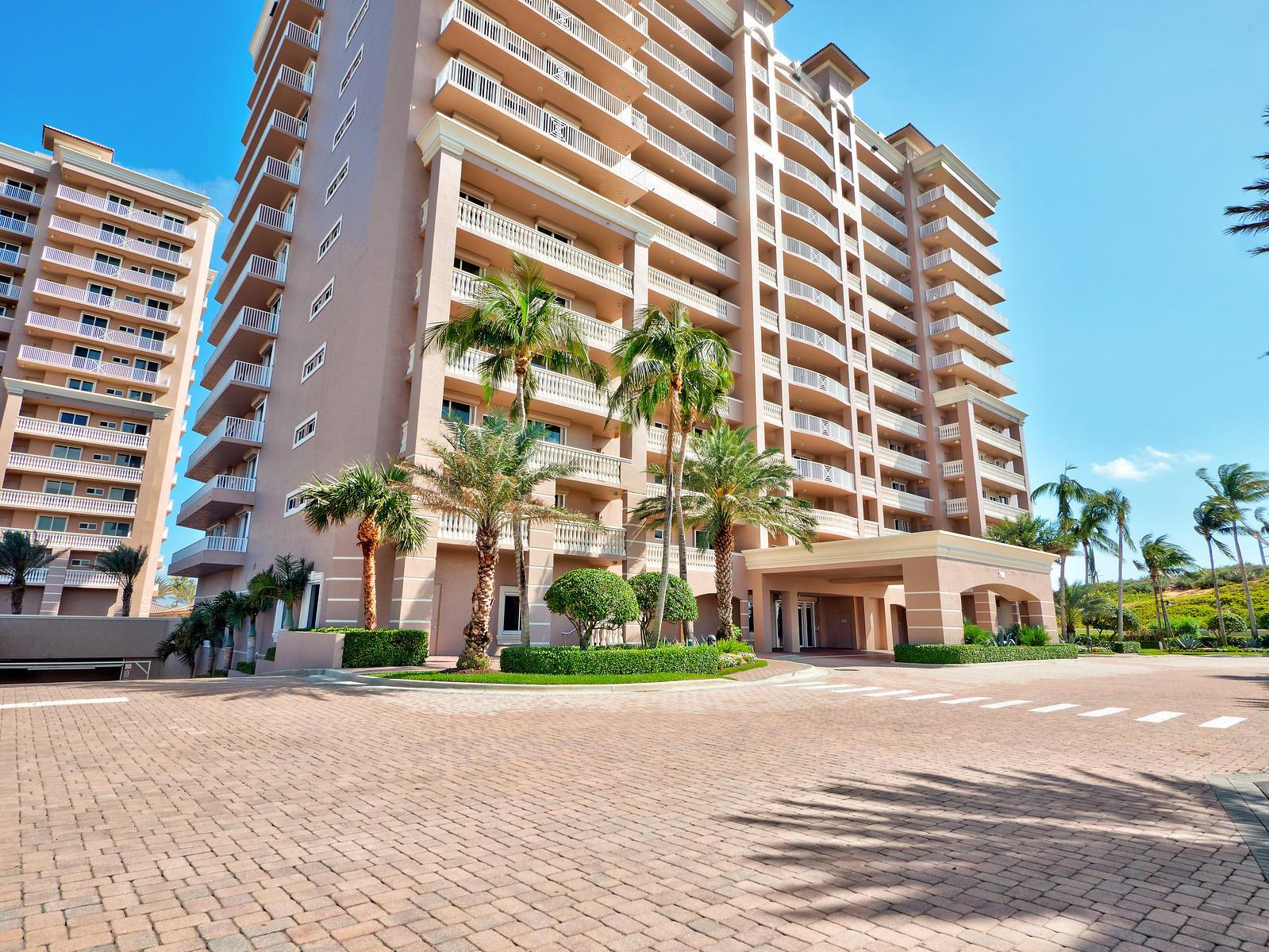 Exterior view of a multi-story tan residential building with balconies and palm trees — 700 Ocean Royale Way # 401, Juno Beach FL 33408, JUNO BEACH, FL