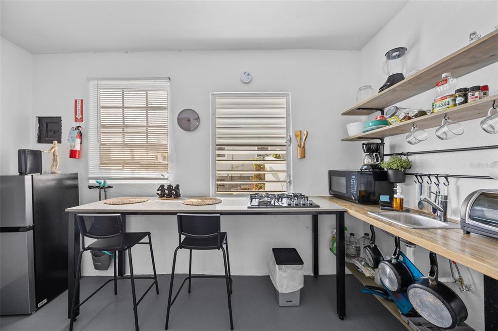 A small kitchen features a central island with a cooktop, open shelving, and a sink — JJ-30 CALLE 10, CAYEY, PR