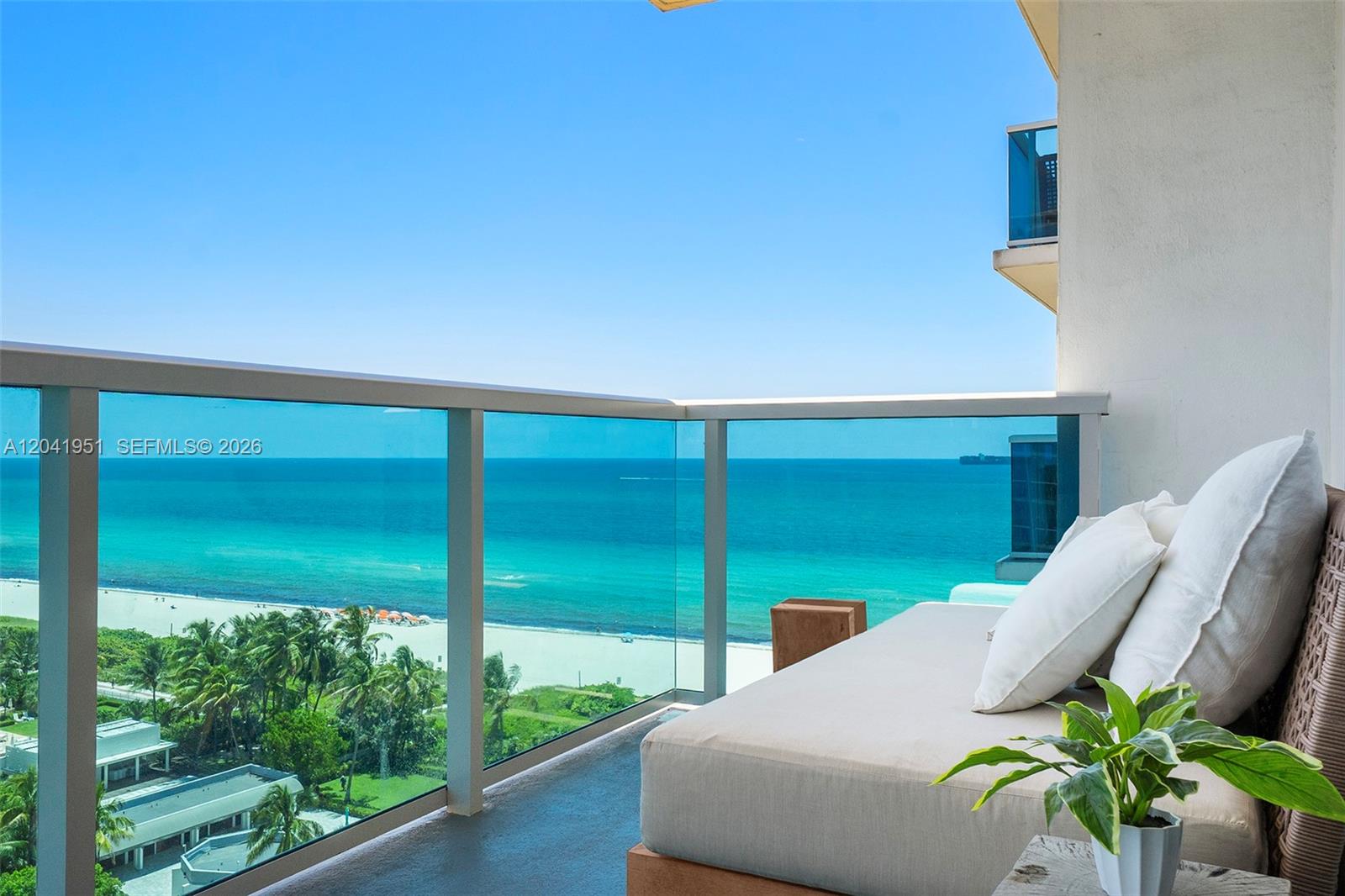 A balcony with a glass railing overlooks a beach and the ocean — 102 24th St # 1213, Miami Beach FL 33139, MIAMI BEACH, FL
