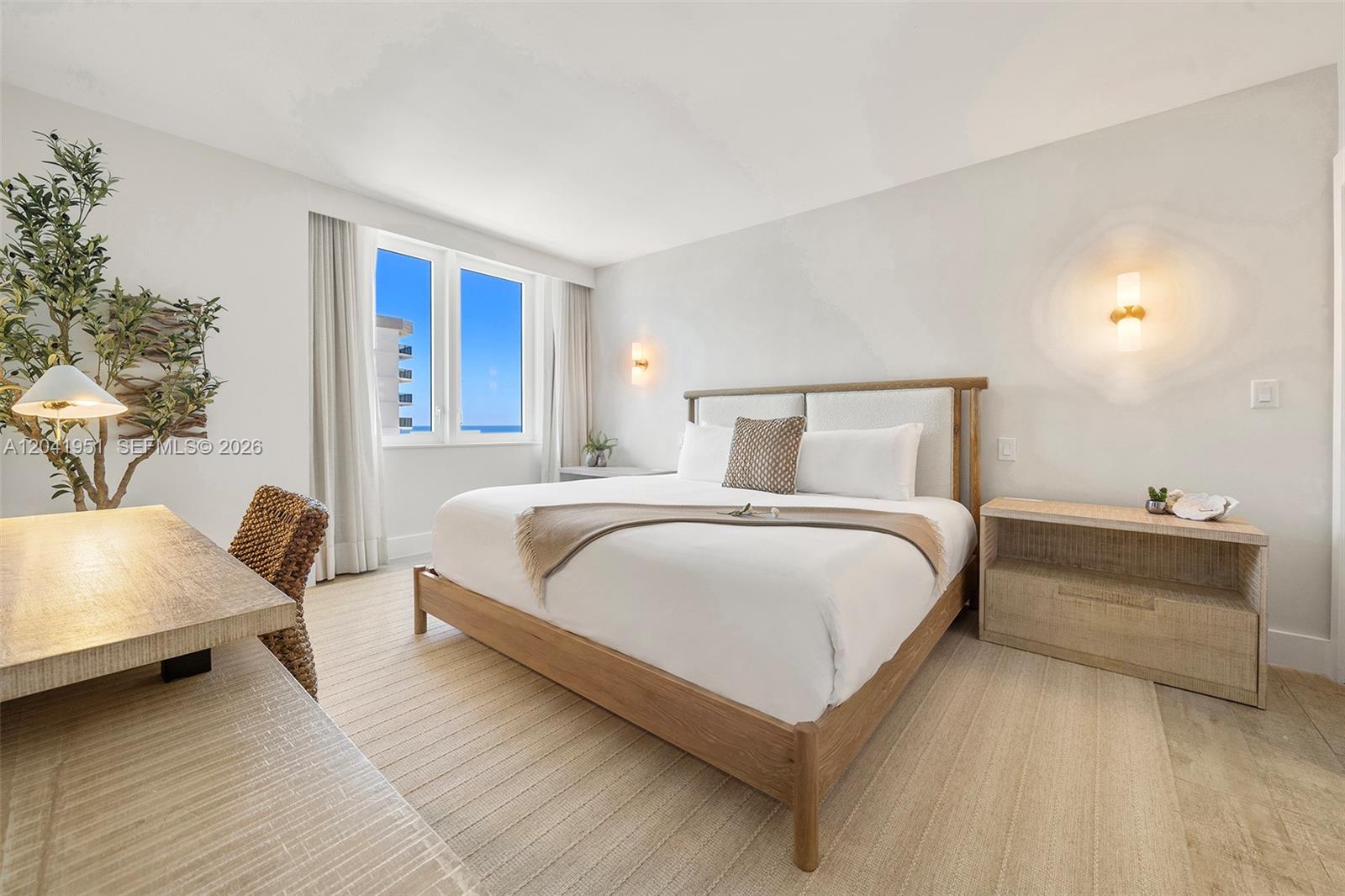 A bedroom features a king bed, light wood furniture, a desk, and an ocean view — 102 24th St # 1213, Miami Beach FL 33139, MIAMI BEACH, FL