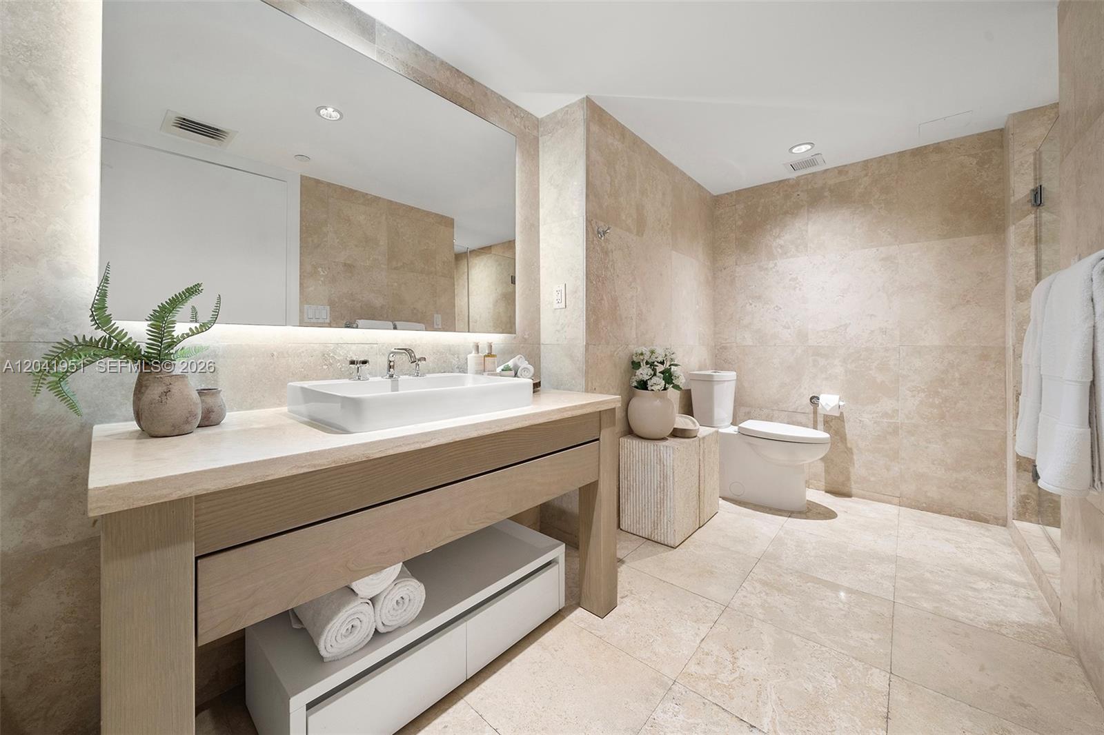 A modern bathroom features a stone-topped vanity, a vessel sink, and beige tile walls — 102 24th St # 1213, Miami Beach FL 33139, MIAMI BEACH, FL