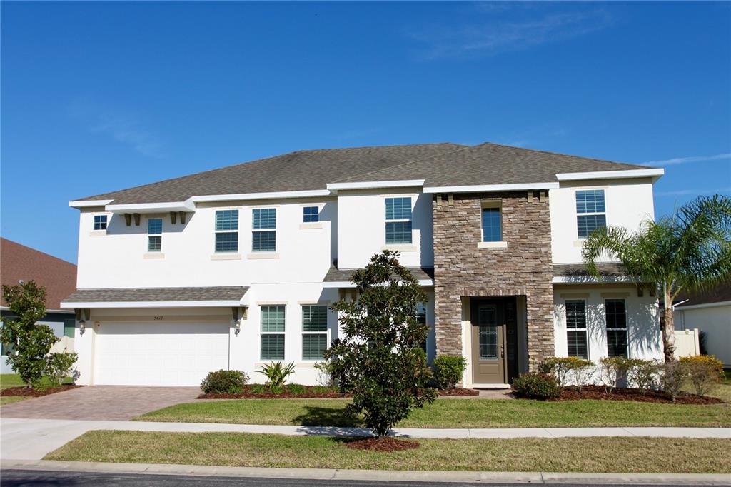 A two-story suburban house with a stone facade, white stucco walls, and a multi-car garage — 5412 CAMBERWELL LANE, RIVERVIEW, FL