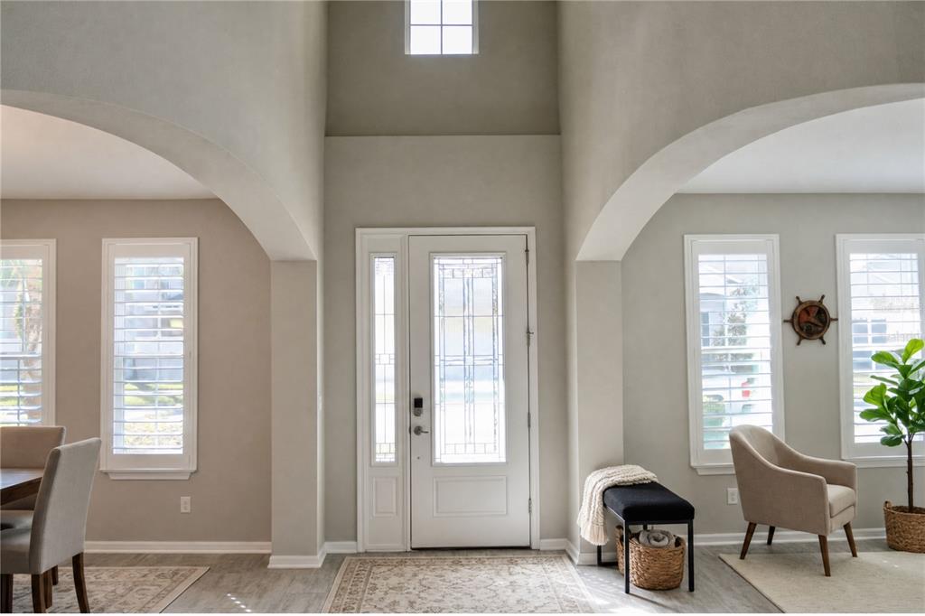 A bright entryway features a white front door, arched openings, and light-colored flooring — 5412 CAMBERWELL LANE, RIVERVIEW, FL