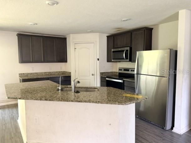 A kitchen features dark wood cabinets, granite countertops, and stainless steel appliances — 3494 APPLE ORCHARD DRIVE, DELTONA, FL