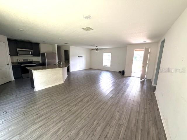An open-concept kitchen and living area feature light wood-look flooring and white walls — 3494 APPLE ORCHARD DRIVE, DELTONA, FL