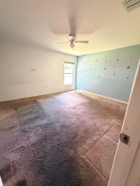 An empty bedroom features beige carpet, a ceiling fan, and a light blue accent wall — 3494 APPLE ORCHARD DRIVE, DELTONA, FL