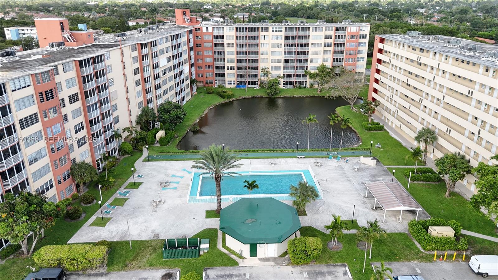 An aerial view shows two apartment buildings surrounding a central swimming pool and pond — 1750 NE 191st St # 1, Miami FL 33179, MIAMI, FL