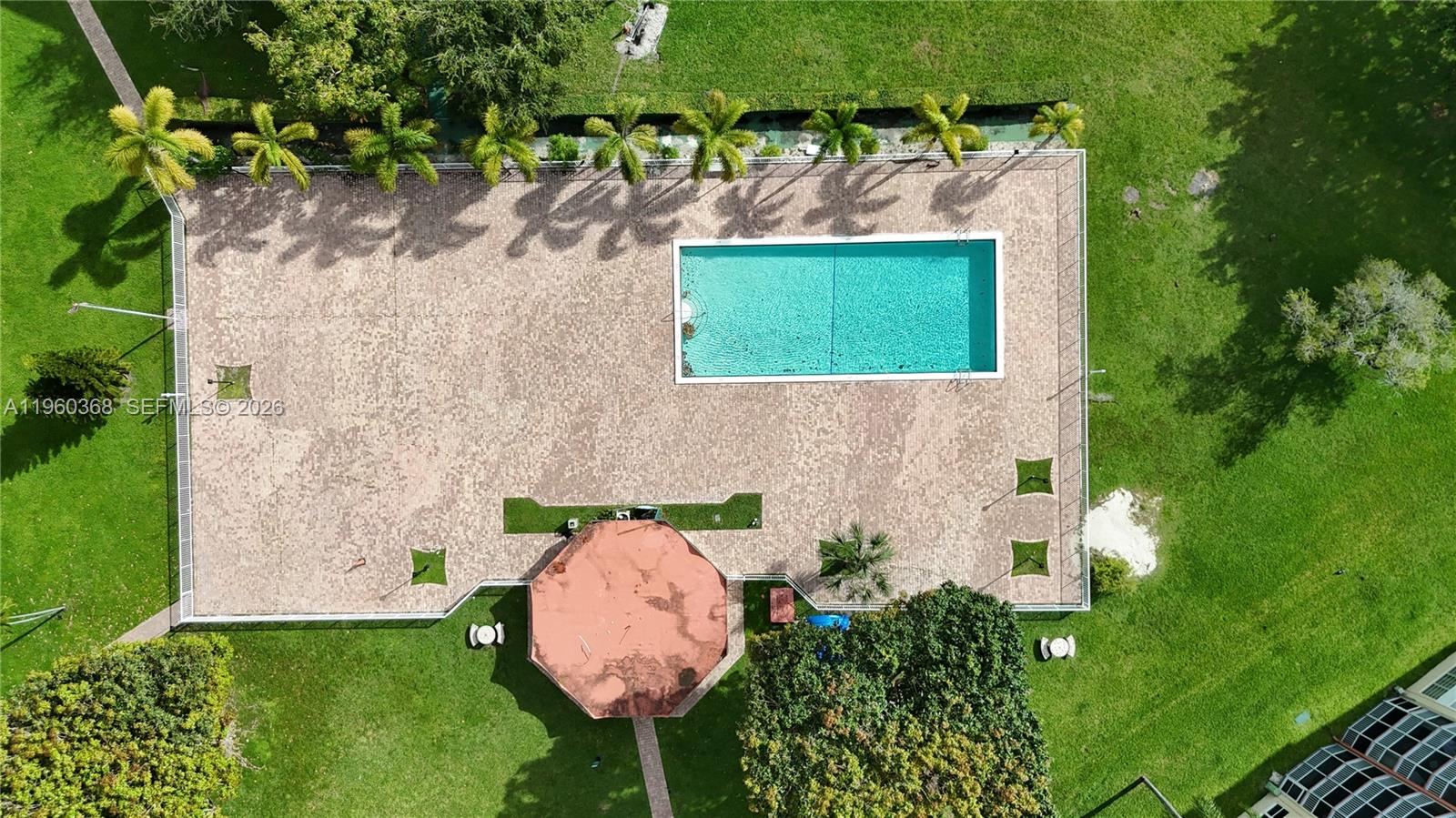 An aerial view shows a rectangular swimming pool on a paved patio with a gazebo — 1750 NE 191st St # 1, Miami FL 33179, MIAMI, FL