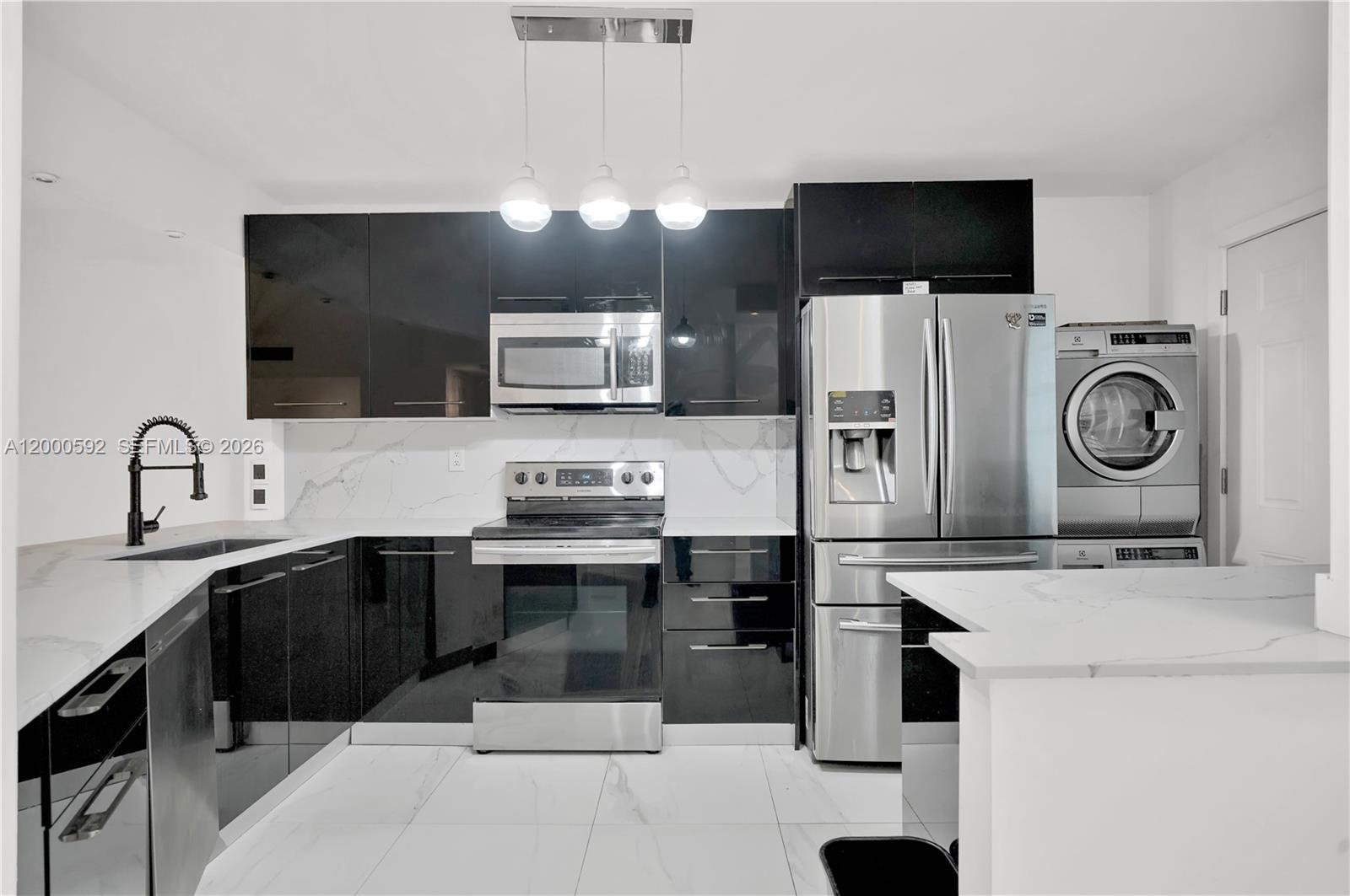 A modern kitchen features black glossy cabinets, stainless steel appliances, and white marble-patterned countertops — 1750 NE 191st St # 2, Miami FL 33179, MIAMI, FL