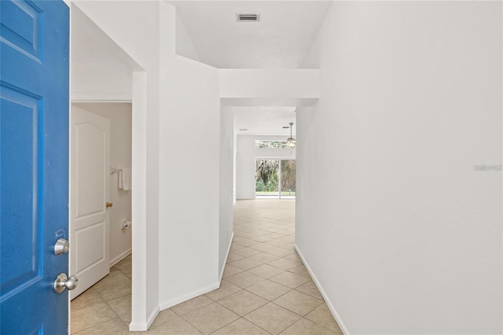 A view from an entryway into a tiled hallway leading toward a living area — 13102 EARLY RUN LANE, RIVERVIEW, FL