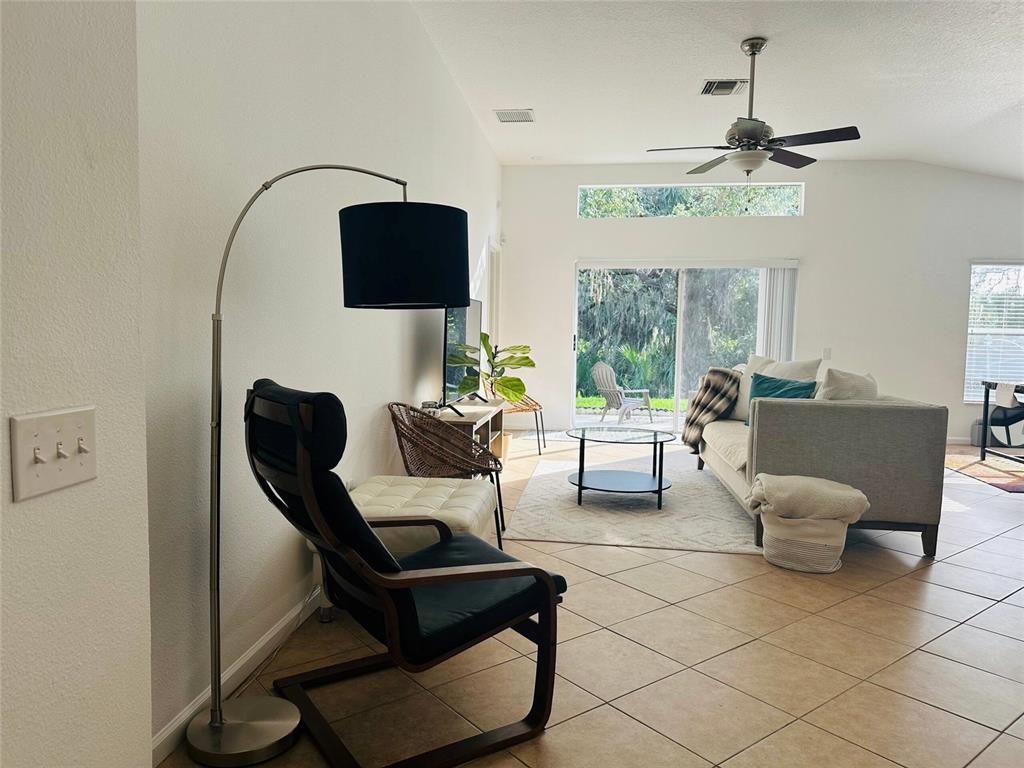 A living room features tile floors, a vaulted ceiling, a ceiling fan, and sliding glass doors — 13102 EARLY RUN LANE, RIVERVIEW, FL