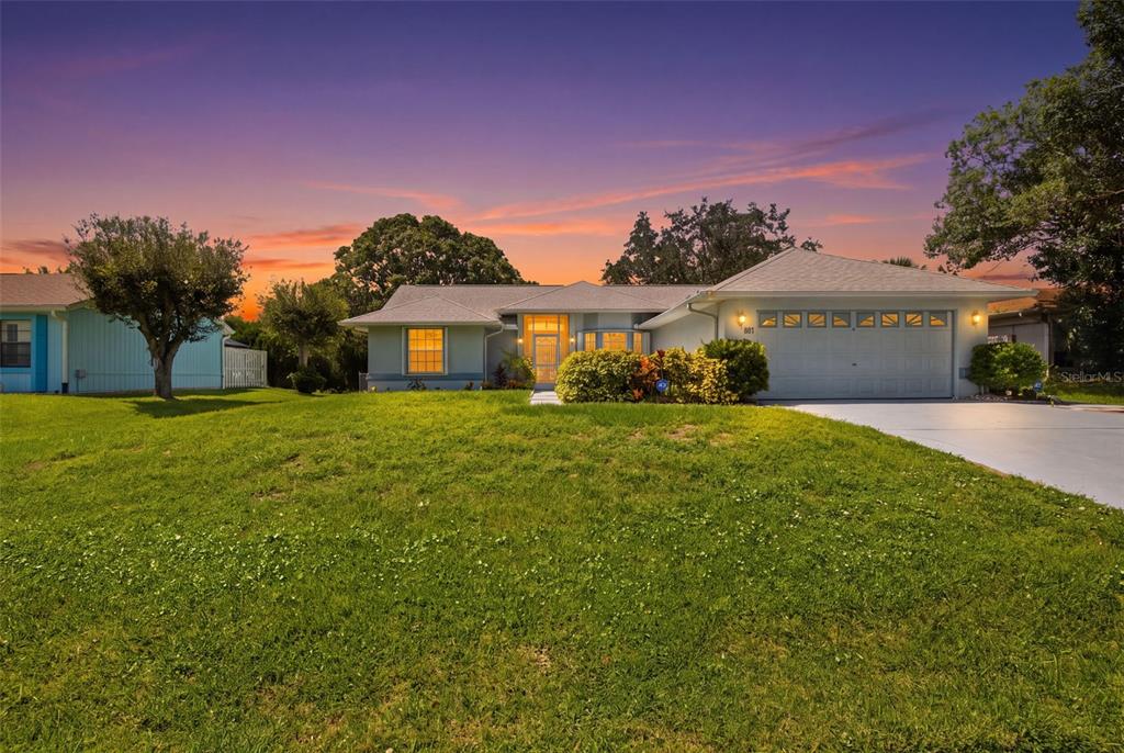 A single-story house with a light blue exterior, a two-car garage, and a grassy lawn — 881 FOSTER AVENUE, SEBASTIAN, FL