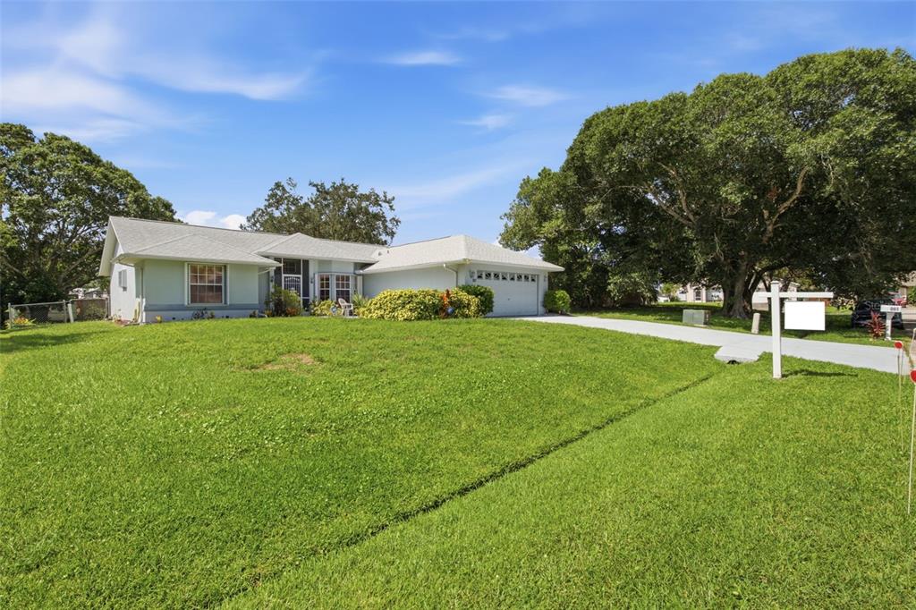A single-story house with a light green exterior, a two-car garage, and a large lawn — 881 FOSTER AVENUE, SEBASTIAN, FL