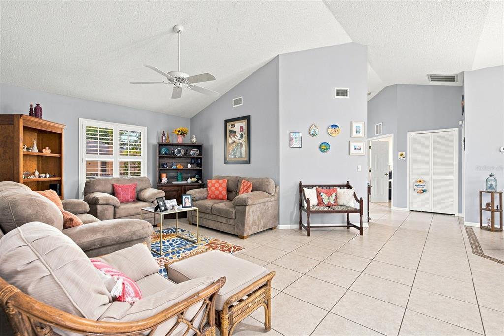 A living room features light gray walls, tile flooring, a vaulted ceiling, and brown furniture — 881 FOSTER AVENUE, SEBASTIAN, FL