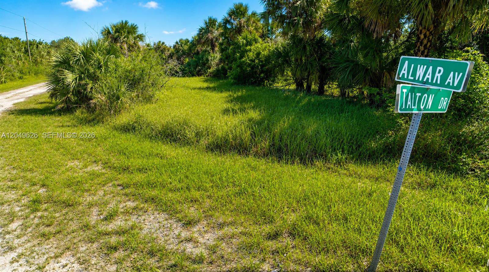 A street sign for Alwar Avenue and Talton Drive stands beside a grassy, undeveloped lot — 2129 ALWAR AVE SW, Palm Bay FL 32908, PALM BAY, FL