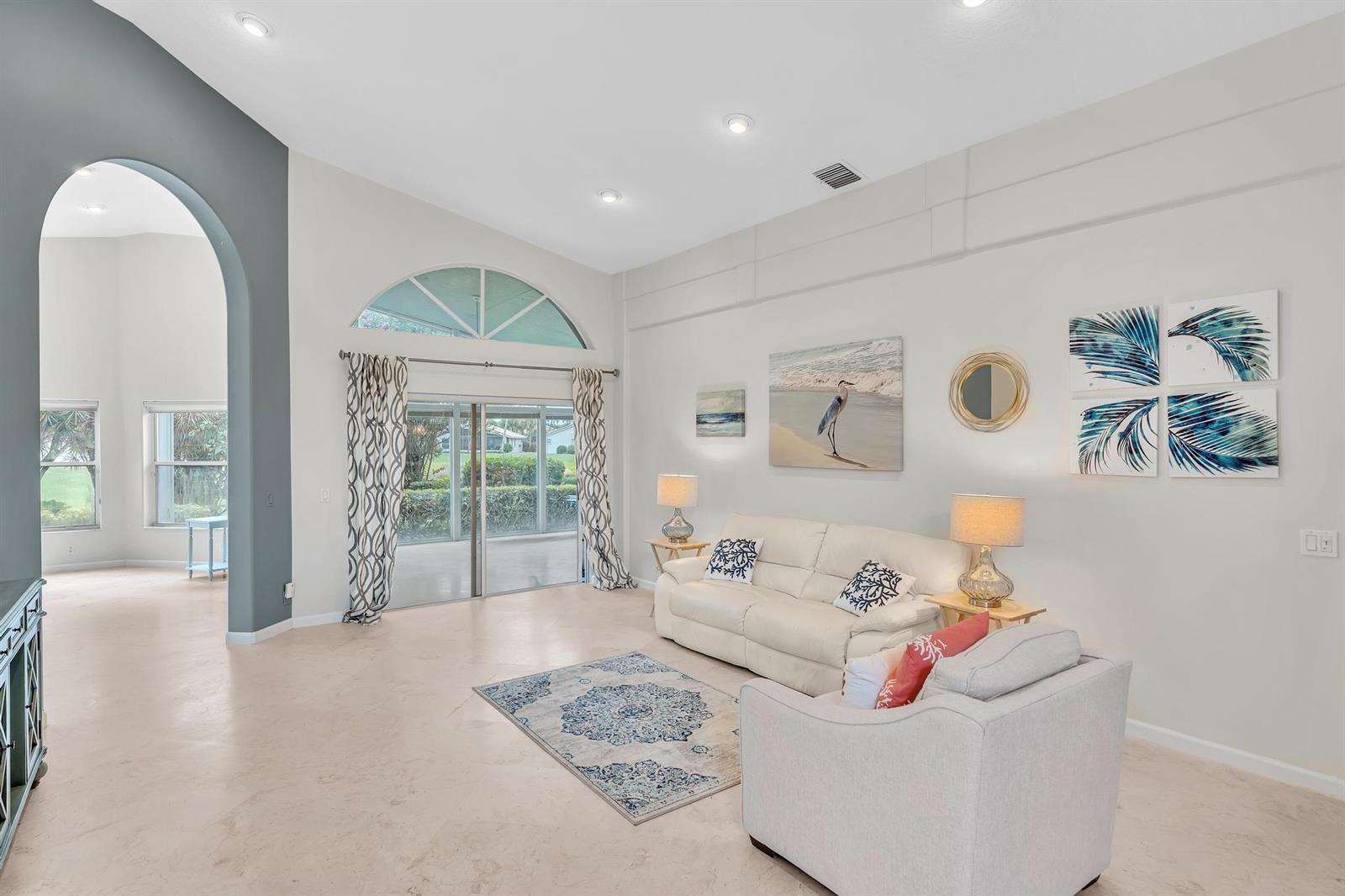 A living room features a white sofa, an armchair, a patterned rug, and arched doorways — 12316 Lakeridge Falls Drive, Boynton Beach FL 33437, BOYNTON BEACH, FL