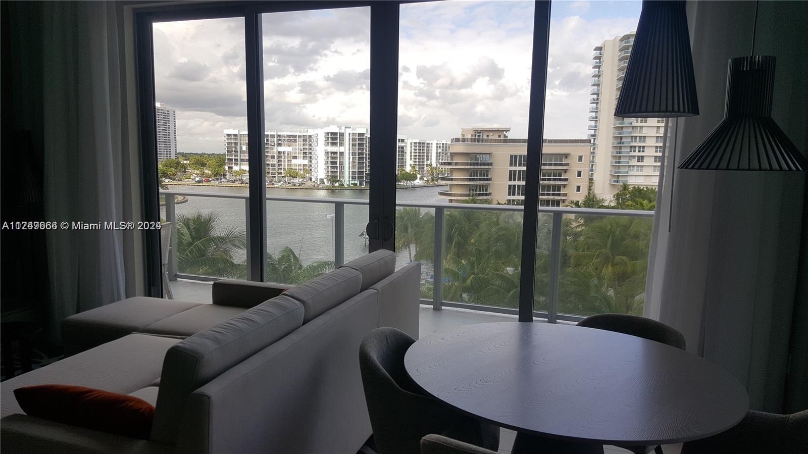 A living and dining area features floor-to-ceiling windows overlooking a waterfront view with high-rise buildings — 4010 S Ocean Dr # R301, Hollywood FL 33019, HOLLYWOOD, FL