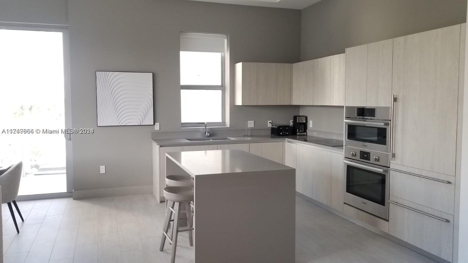 A modern kitchen features light wood cabinetry, a central island, and stainless steel built-in appliances — 4010 S Ocean Dr # R301, Hollywood FL 33019, HOLLYWOOD, FL