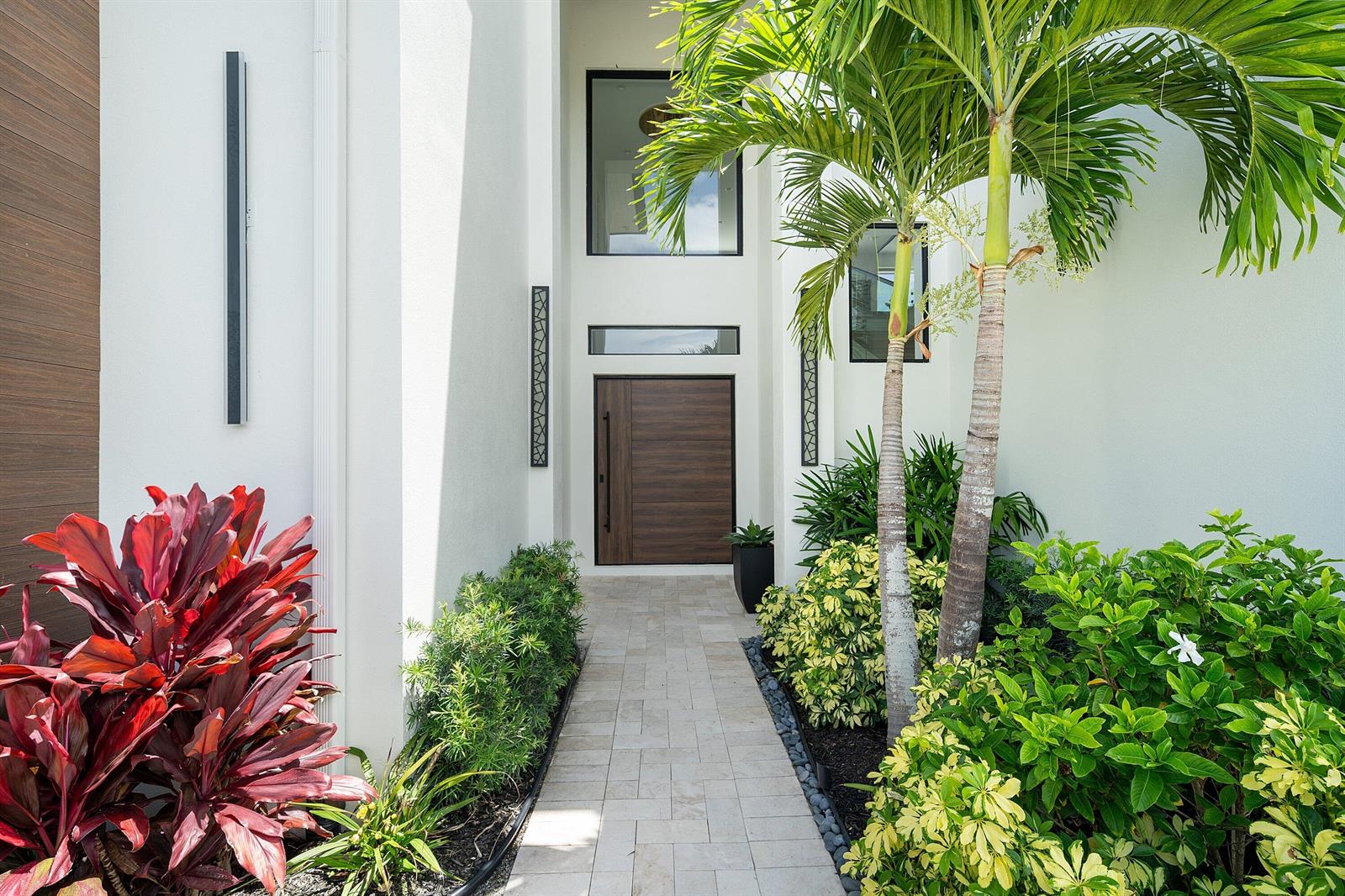A stone walkway leads to a modern front door flanked by tropical plants and palms — 798 Havana Drive, Boca Raton FL 33487, BOCA RATON, FL