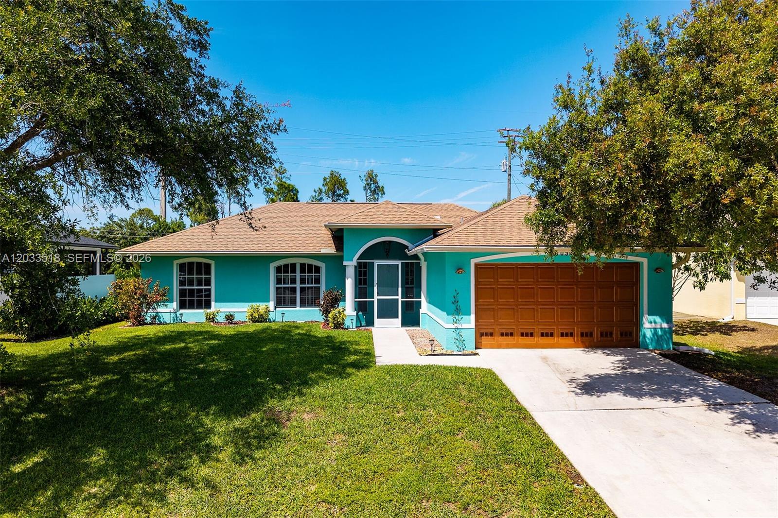 A single-story house with turquoise stucco walls, a brown garage door, and a shingled roof — 2009 SW 36th Ter, Cape Coral FL 33914, CAPE CORAL, FL