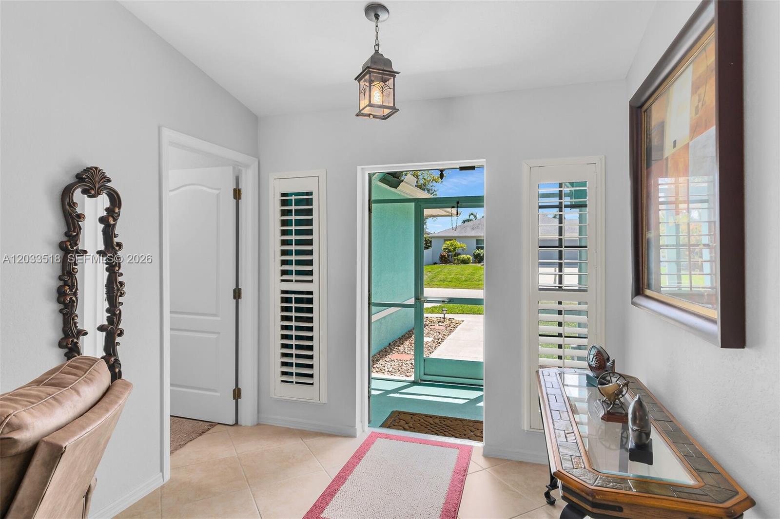 An entryway features tile flooring, a glass-topped console table, a mirror, and a screen door — 2009 SW 36th Ter, Cape Coral FL 33914, CAPE CORAL, FL