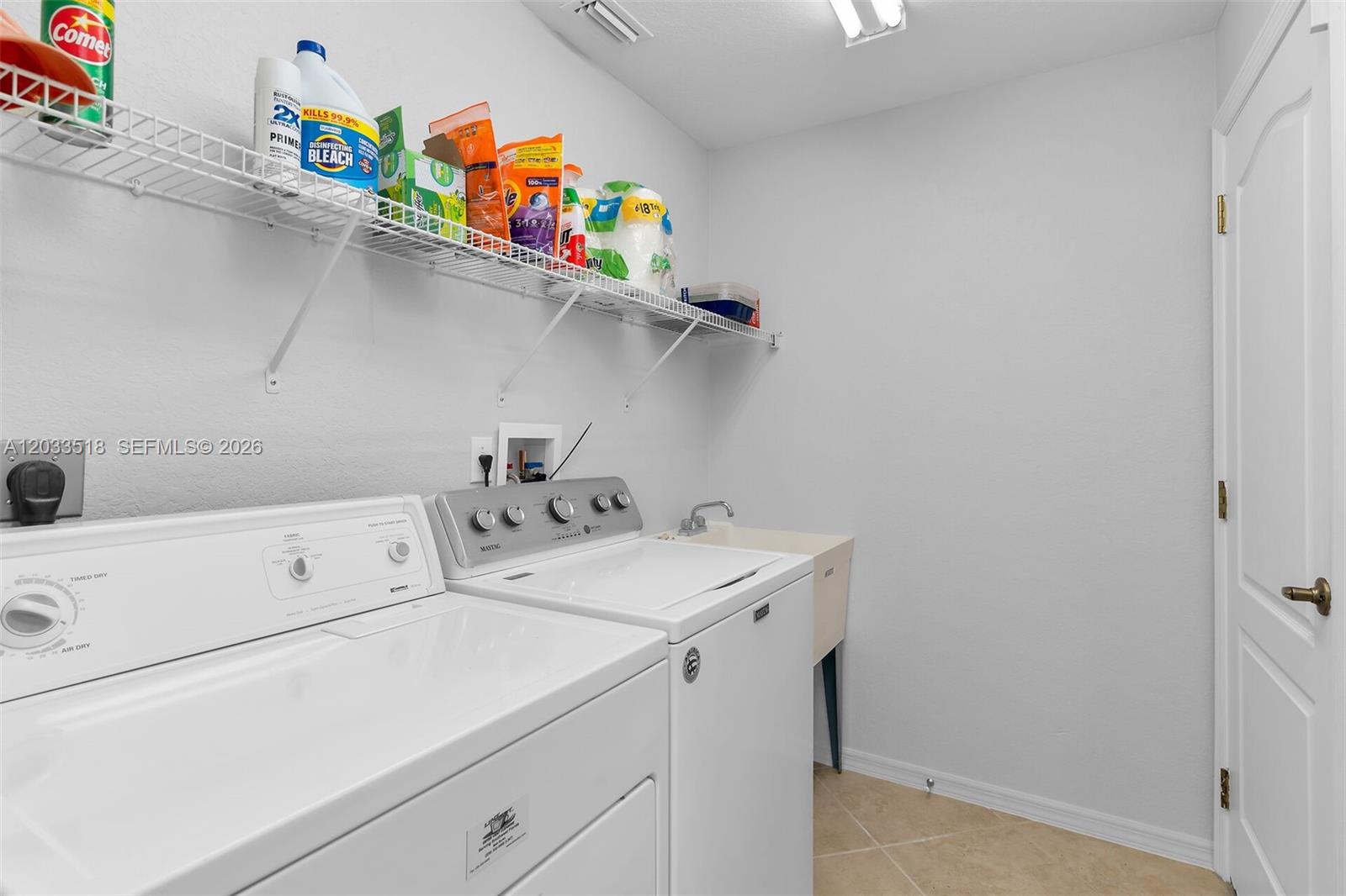 A laundry room features a white washer and dryer, a utility sink, and wire shelving — 2009 SW 36th Ter, Cape Coral FL 33914, CAPE CORAL, FL