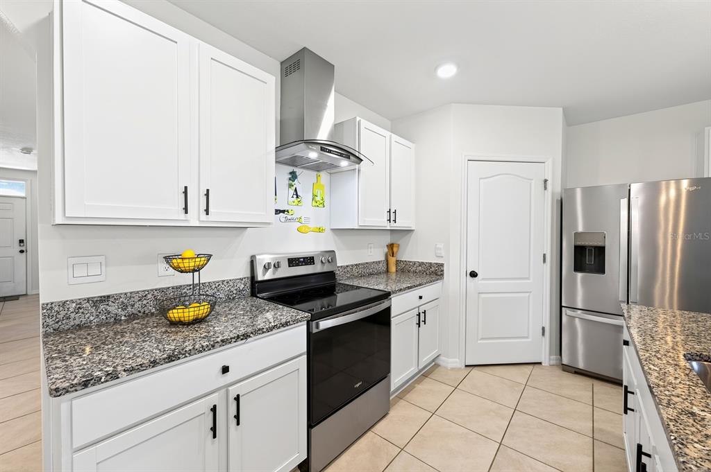 A kitchen with white cabinets, granite countertops, stainless steel appliances, and tile flooring — 1191 ABAGAIL DRIVE, DELTONA, FL