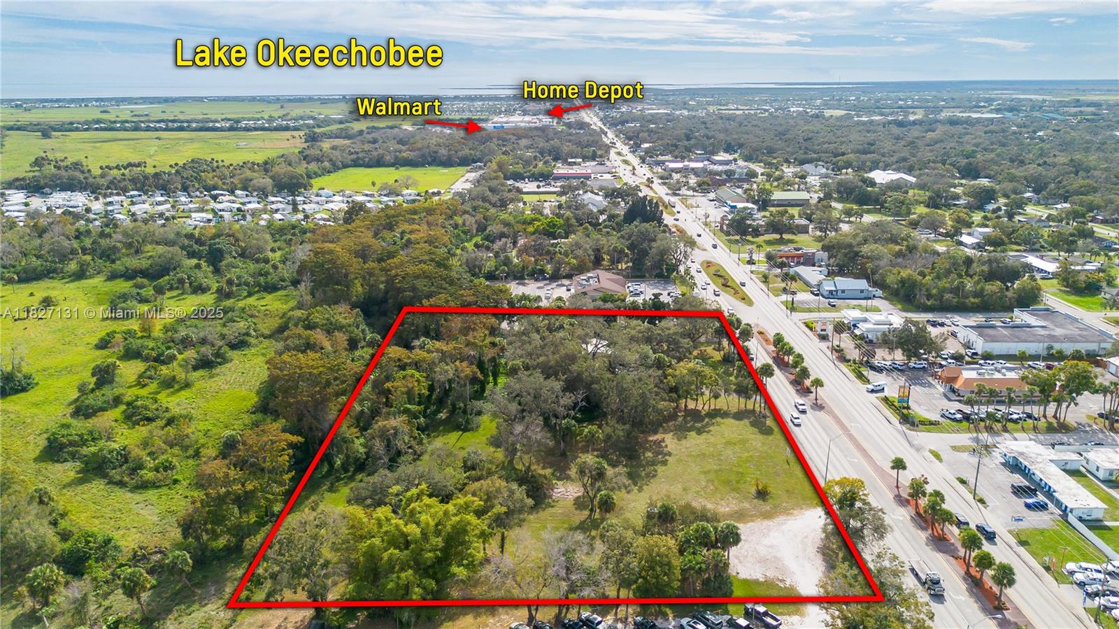 This aerial view shows a vacant, tree-covered lot outlined in red next to a highway — 1011 S. PARROTT, Okeechobee FL 34972, OKEECHOBEE, FL