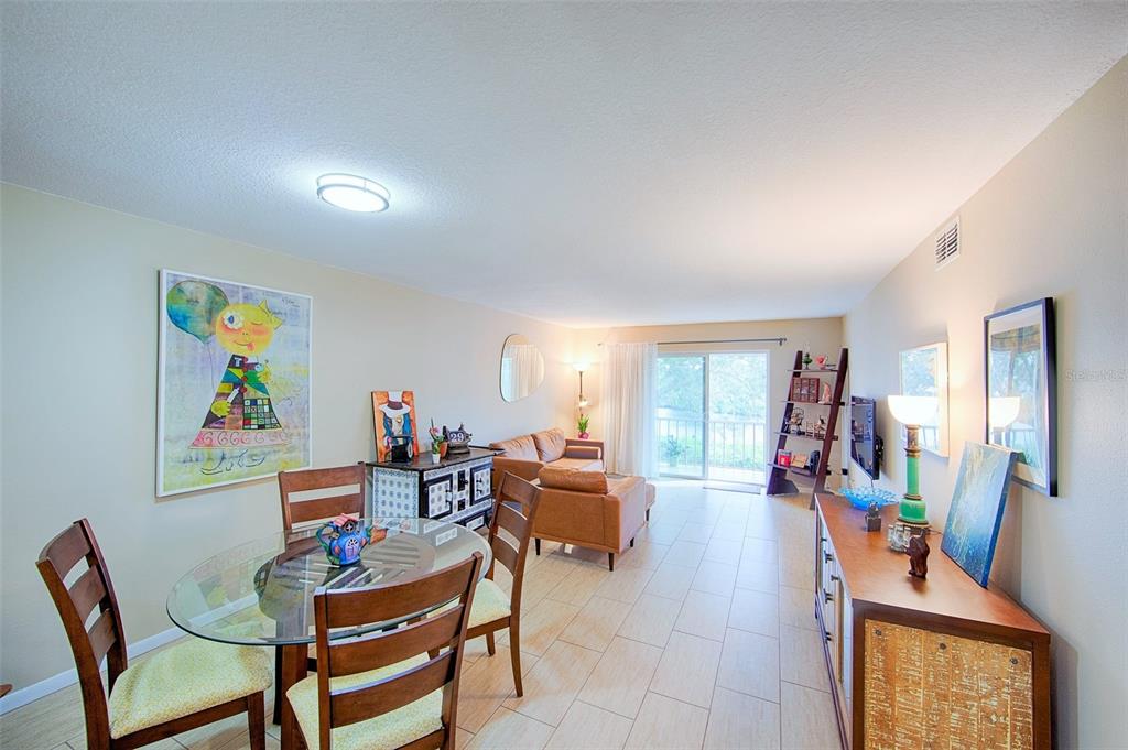 A dining area and living room with tile floors, a glass table, and sliding doors — 1860 MASSACHUSETTS AVENUE NE UNIT 224, ST PETERSBURG, FL