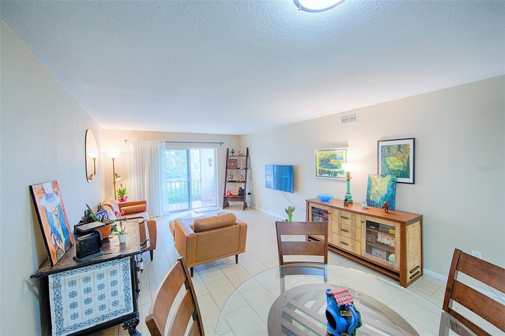 A living room and dining area feature tile flooring, a glass table, and neutral walls — 1860 MASSACHUSETTS AVENUE NE UNIT 224, ST PETERSBURG, FL