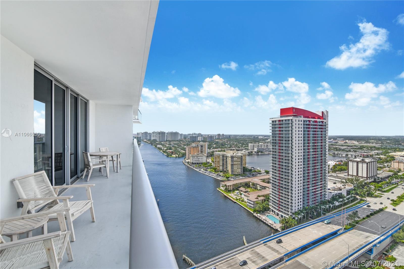 A high-rise balcony with patio furniture overlooks a river, a bridge, and city buildings — 4010 S Ocean Dr # R1406, Hollywood FL 33019, HOLLYWOOD, FL