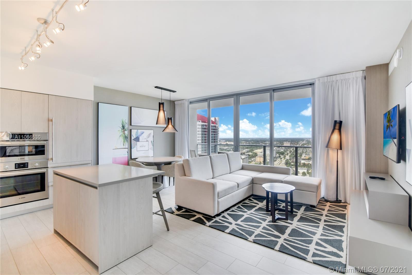 A modern open-concept living room and kitchen area with floor-to-ceiling windows and city views — 4010 S Ocean Dr # R1406, Hollywood FL 33019, HOLLYWOOD, FL