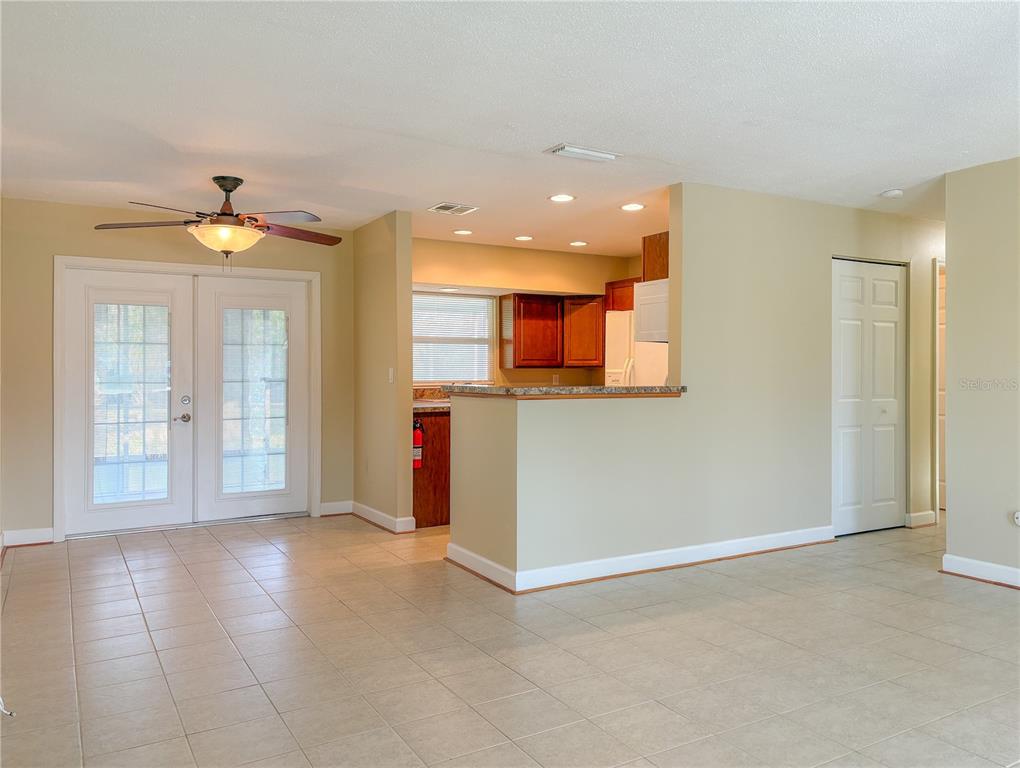A room with tile flooring, a ceiling fan, French doors, and an open kitchen area — 389 MILLPORT STREET NW, PORT CHARLOTTE, FL