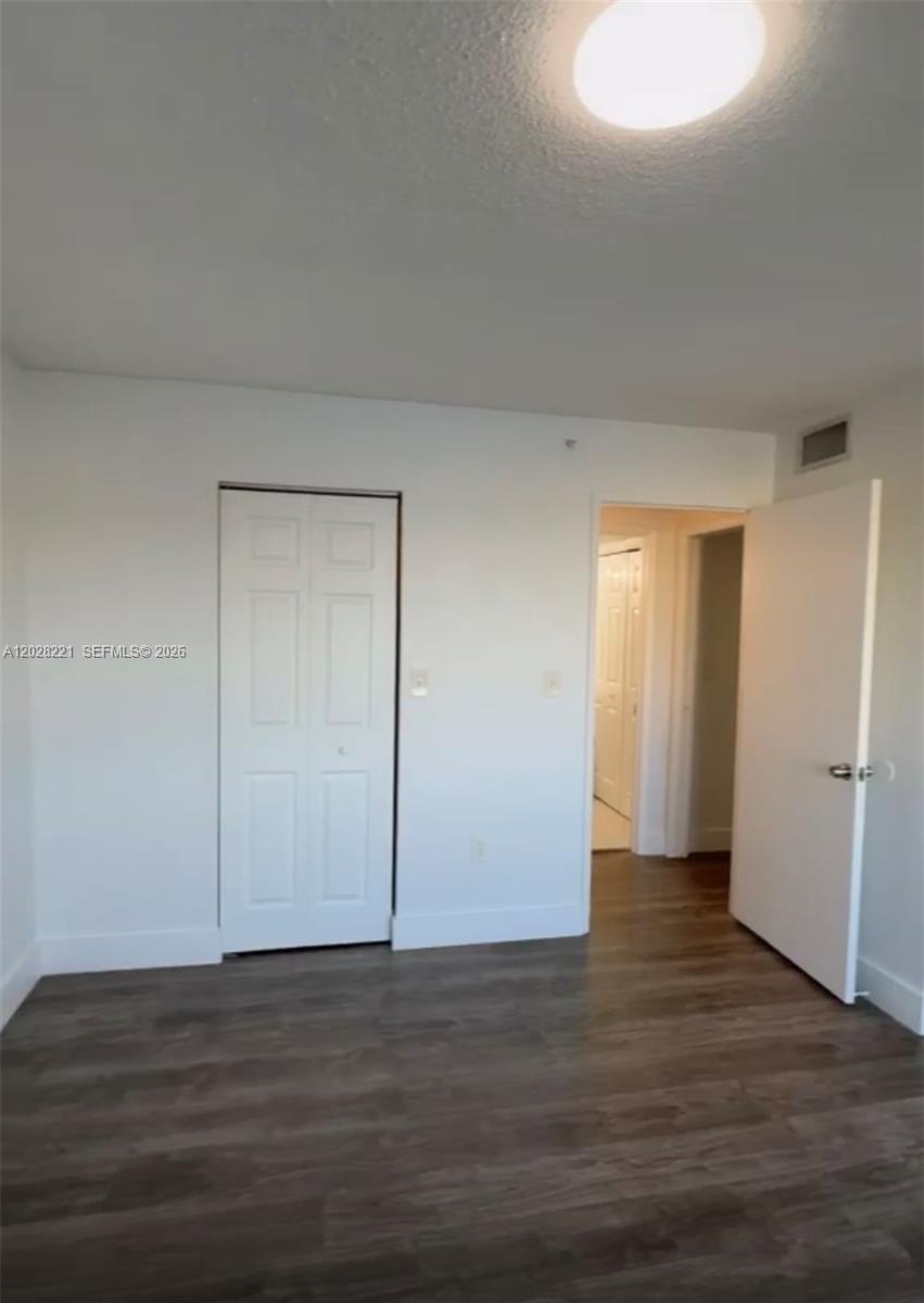 A bedroom features white walls, a white closet door, and dark wood-look flooring — 4420 NW 107th Ave # 206, Doral FL 33178, DORAL, FL