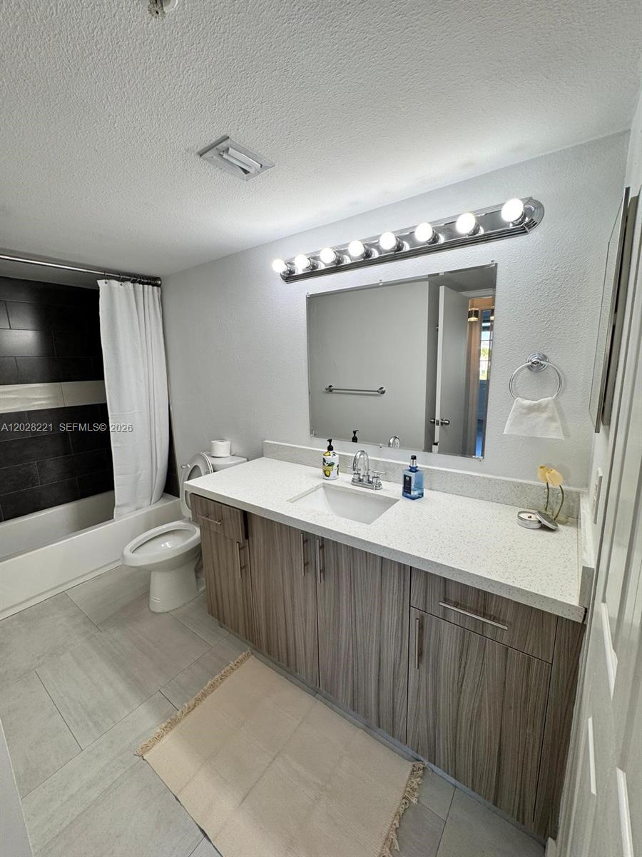 A bathroom features a wood-grain vanity, white quartz countertop, and a black-tiled shower area — 4420 NW 107th Ave # 206, Doral FL 33178, DORAL, FL