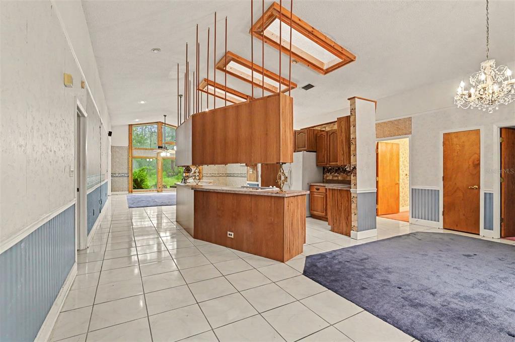 A kitchen with wood cabinets and a hanging storage unit overlooks a living area — 1235 MARSH FERN ROAD, MIMS, FL