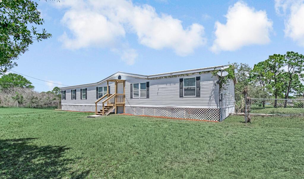 A single-story manufactured home with light gray siding and a wooden front porch — 545 Bald Cypress Avenue, Clewiston FL 33440, CLEWISTON, FL