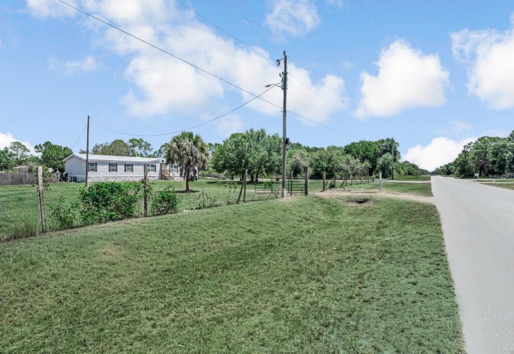 A grassy lot with a fence, a utility pole, and a house in the distance — 545 Bald Cypress Avenue, Clewiston FL 33440, CLEWISTON, FL