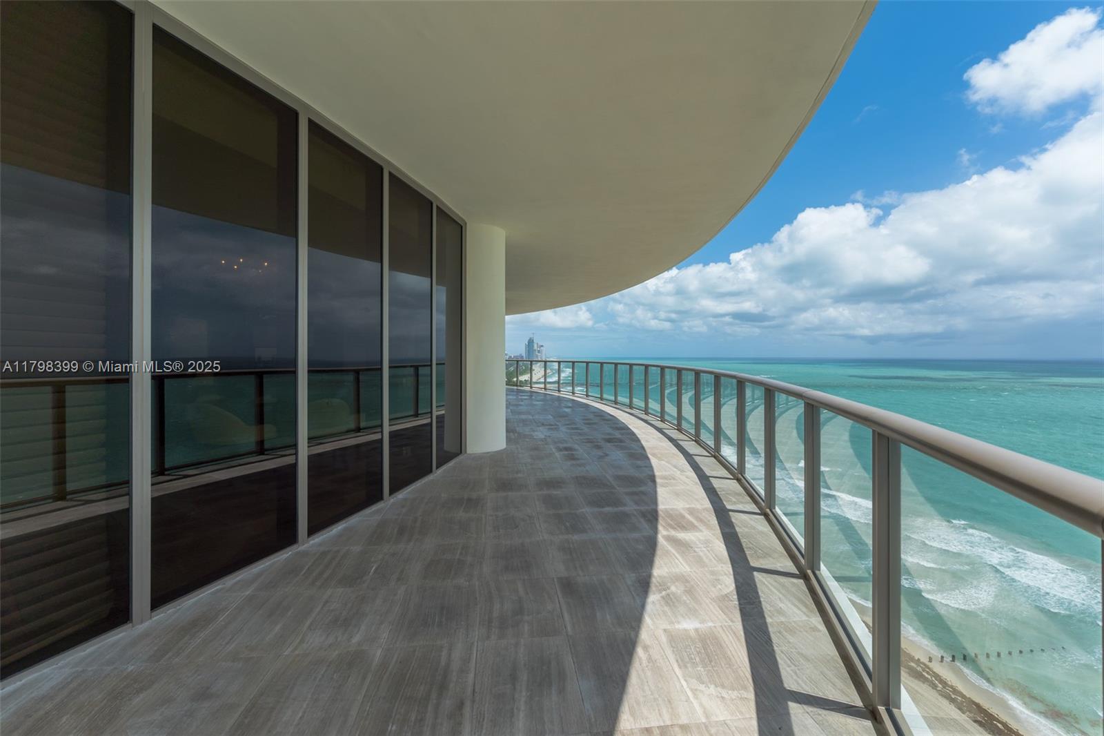 A curved balcony features tiled flooring, glass railings, and expansive ocean views — 9703 Collins Ave # 2100, Bal Harbour FL 33154, BAL HARBOUR, FL