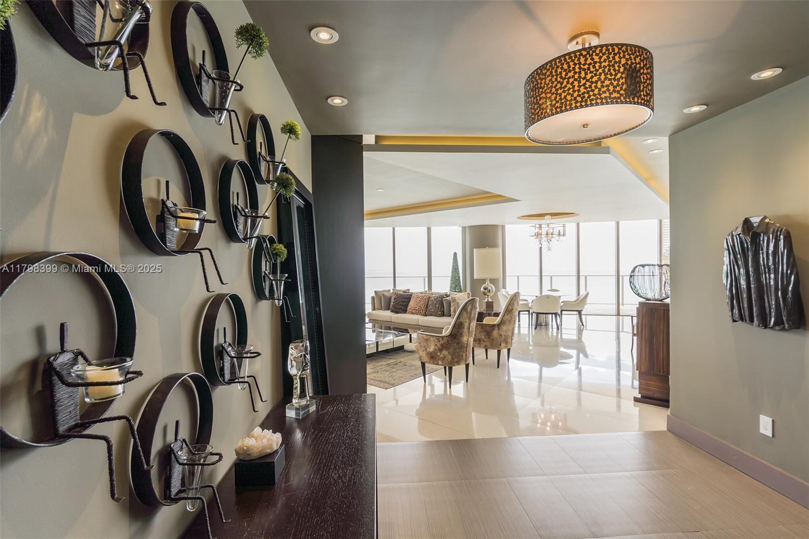 A modern foyer features a wall of circular candle holders leading into a bright living area — 9703 Collins Ave # 2100, Bal Harbour FL 33154, BAL HARBOUR, FL