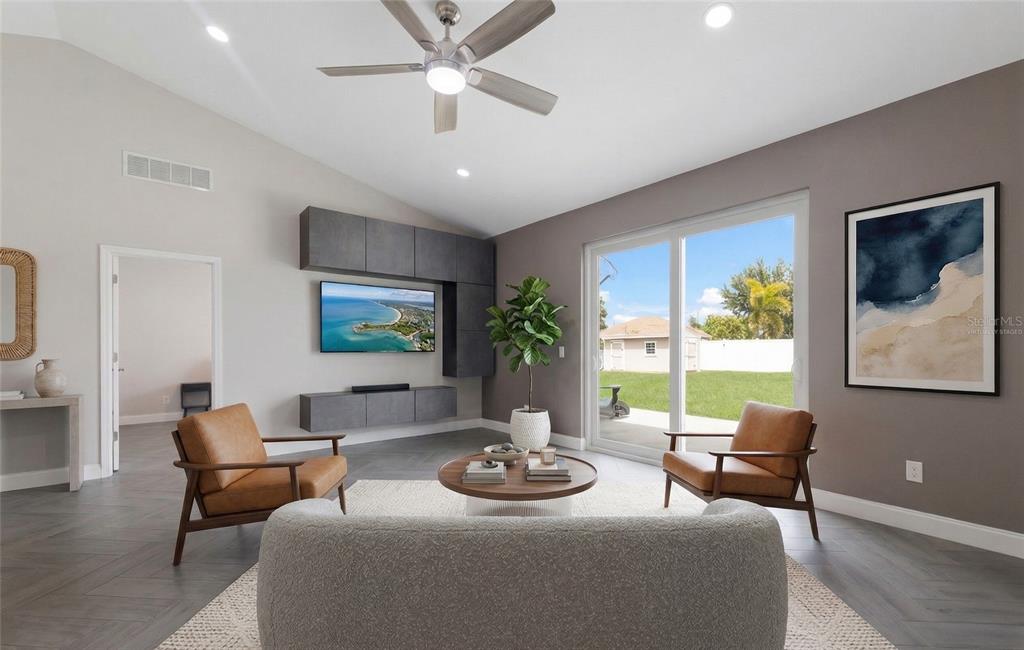A living room features gray herringbone floors, a wall-mounted television, and two leather armchairs — 1606 22ND AVENUE W, PALMETTO, FL