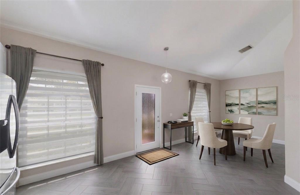 A dining area with a round table, chairs, and a front door with herringbone flooring — 1606 22ND AVENUE W, PALMETTO, FL
