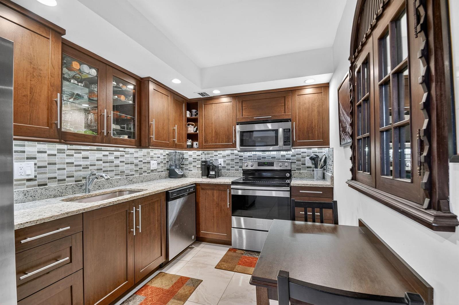 A kitchen features dark wood cabinets, stainless steel appliances, granite countertops, and a tiled backsplash — 3450 S Ocean Boulevard # 423, Palm Beach FL 33480, PALM BEACH, FL