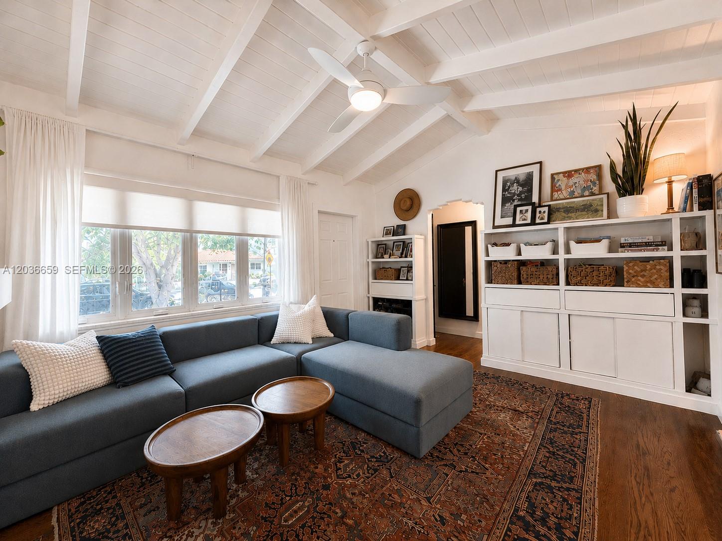 A living room features a blue sectional sofa, wooden coffee tables, and built-in white shelving — 454 NE 76th St, Miami FL 33138, MIAMI, FL