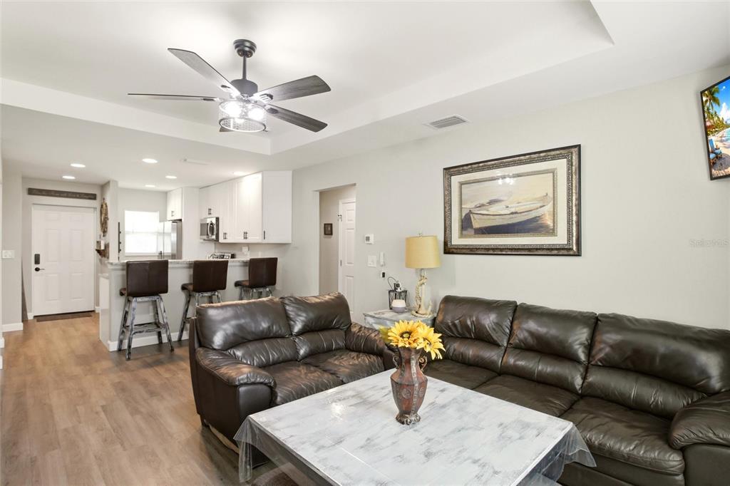 A living room with dark leather sofas, a coffee table, and an open kitchen area — 28111 MANFRED DRIVE, PUNTA GORDA, FL