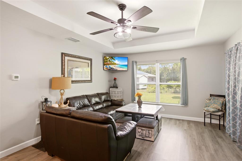 A living room features a dark leather sofa, a ceiling fan, and a corner-mounted television — 28111 MANFRED DRIVE, PUNTA GORDA, FL
