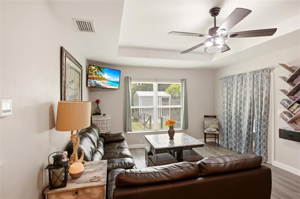 A living room with a brown leather sofa, ceiling fan, and a window view — 28111 MANFRED DRIVE, PUNTA GORDA, FL